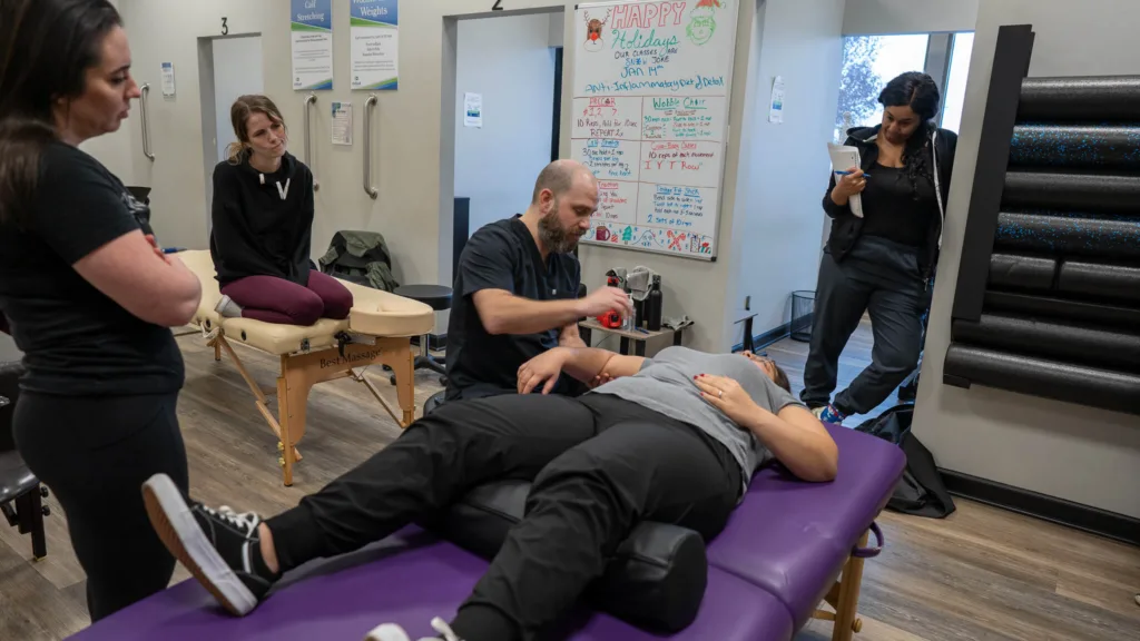 Dr. Christopher Allin provides real-time feedback while students practice neuromyofascial therapy techniques on a patient.